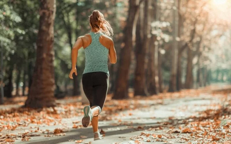 Eine Frau joggt durch einen Wald.