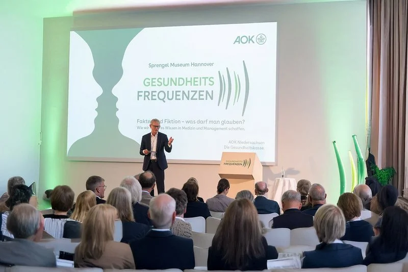 Ein Redner spricht vor einer Gruppe Veranstaltungsteilnehmer