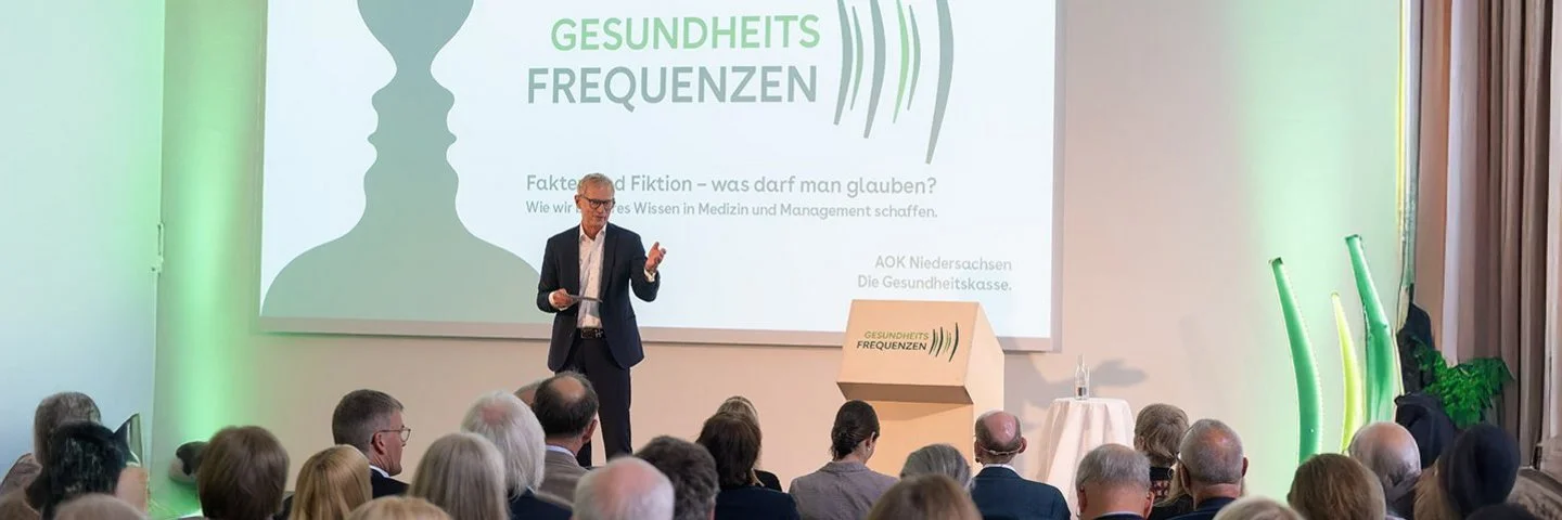 Ein Redner spricht vor einer Gruppe Veranstaltungsteilnehmer