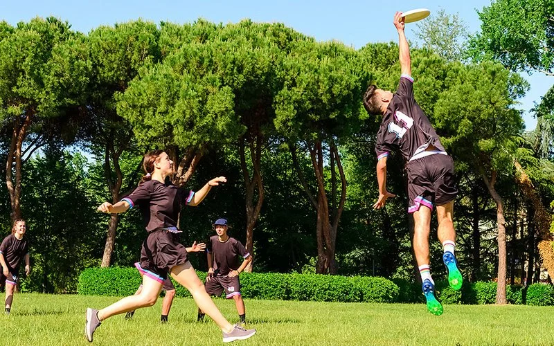 Ein gemischtes Team spielt Ultimate Frisbee im Park.