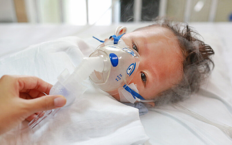 Kleiner Junge mit RSV-Infektion bekommt Inhalationsmedikamente per Inhalationsmaske.