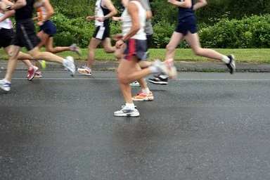 Läufergruppe in Sportkleidung läuft auf nasser Straße bei einem Firmenlauf