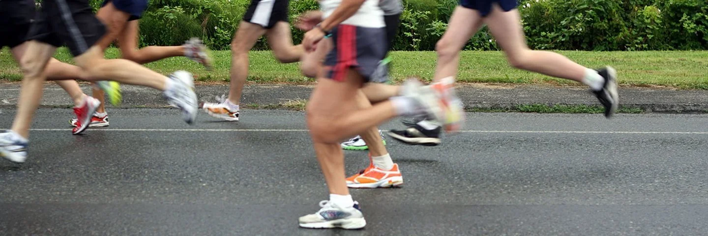 Läufergruppe in Sportkleidung läuft auf nasser Straße bei einem Firmenlauf