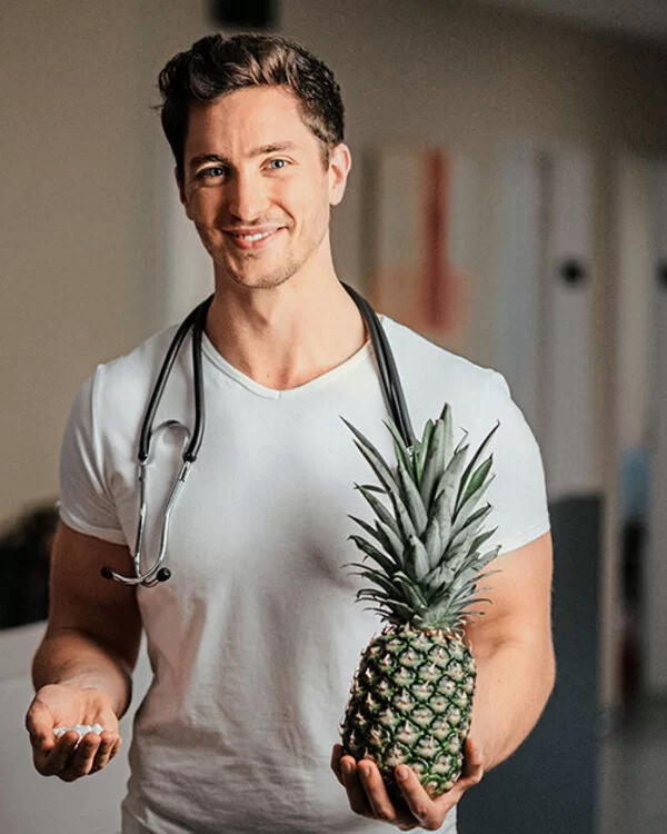 Portraitfoto des Medfluencers Felix Bernd, der eine Ananas in der linken Hand hält.