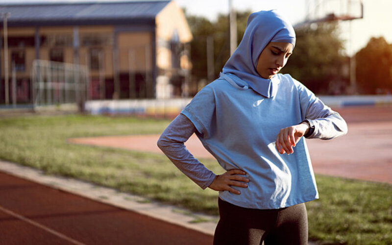 Junge Sportlerin misst ihre Herzfrequenz, um einen Runner’s High zu begünstigen.