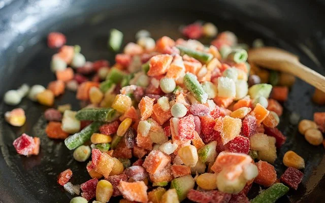 Nahaufnahme von gefrorenem Gemüse in einer Bratpfanne.