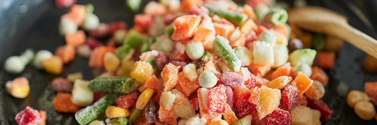 Nahaufnahme von gefrorenem Gemüse in einer Bratpfanne.