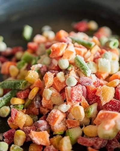 Nahaufnahme von gefrorenem Gemüse in einer Bratpfanne.