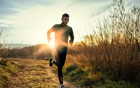 Ein Mann joggt auf einem Feldweg in den Morgenstunden.