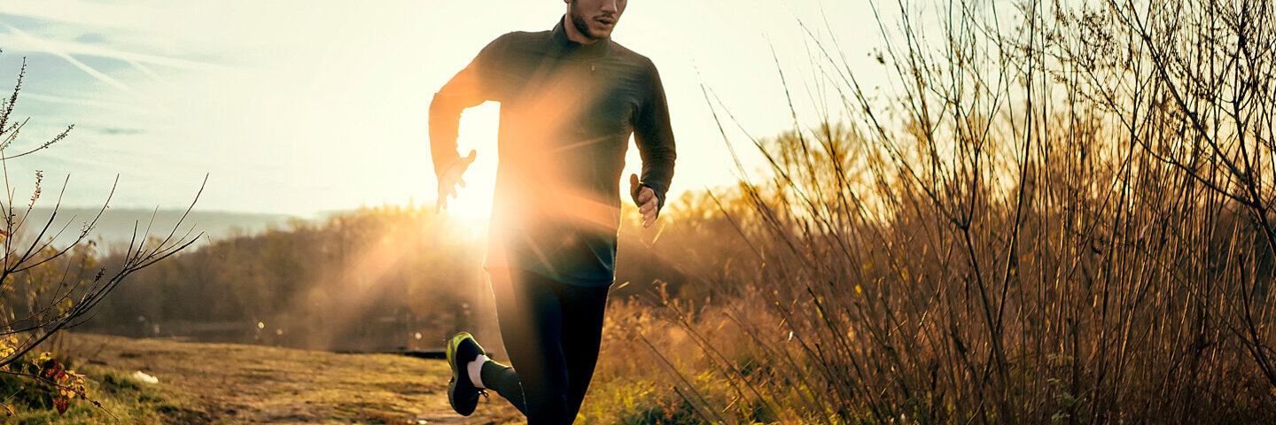 Ein Mann joggt auf einem Feldweg in den Morgenstunden.