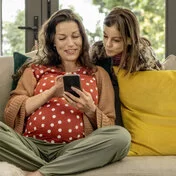 Eine schwanger Frau und ein Kind recherchieren gemeinsam auf dem Smartphone. Die App “AOK Schwanger” liefert wichtige Informationen.
