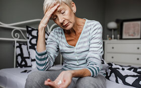 Älterer Frau geht es nicht gut, weshalb sie eine Schmerztablette nehmen will.