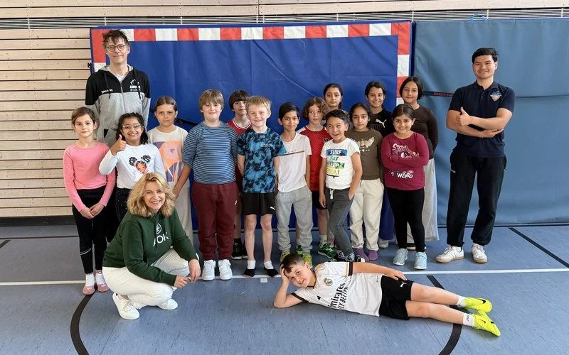Schulklasse mit Trainerteam und AOK-Begleitung in der Sporthalle beim Bewegungsprojekt Ahorn@school