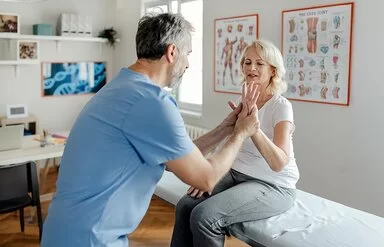 Ein Physiotherapeut bei der Arbeit mit einer älteren Patientinnen in der Klinik