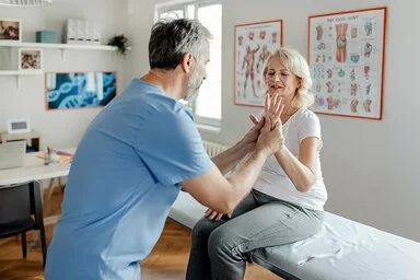 Ein Physiotherapeut bei der Arbeit mit einer älteren Patientinnen in der Klinik