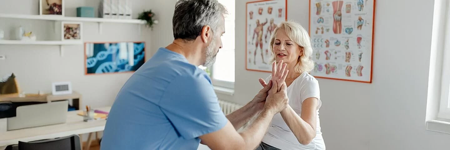 Ein Physiotherapeut bei der Arbeit mit einer älteren Patientinnen in der Klinik
