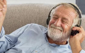 Ein älterer Herr genießt Musik hören über Kopfhörer