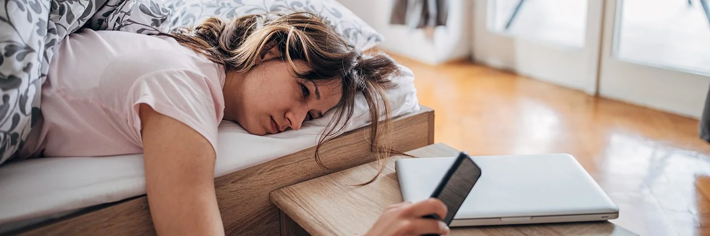 Junge Frau liegt noch müde am Morgen im Bett – sie hat zu viel geschlafen.