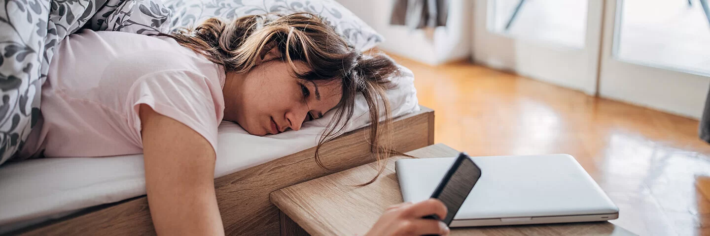 Junge Frau liegt noch müde am Morgen im Bett – sie hat zu viel geschlafen.