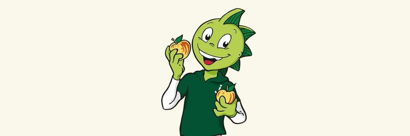 Jolinchen steht vor einem gelben Hintergrund und hält lachend zwei Äpfel in den Händen.