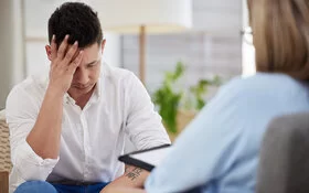 Mann mit einer posttraumatischen Belastungsstörung spricht mit seiner Psychotherapeutin.