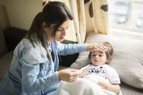 Eine Mutter misst Fieber bei ihrer Tochter. Leiden Kinder an einer Mittelohrentzündung, verordnen Ärzte oft Schmerzmittel.