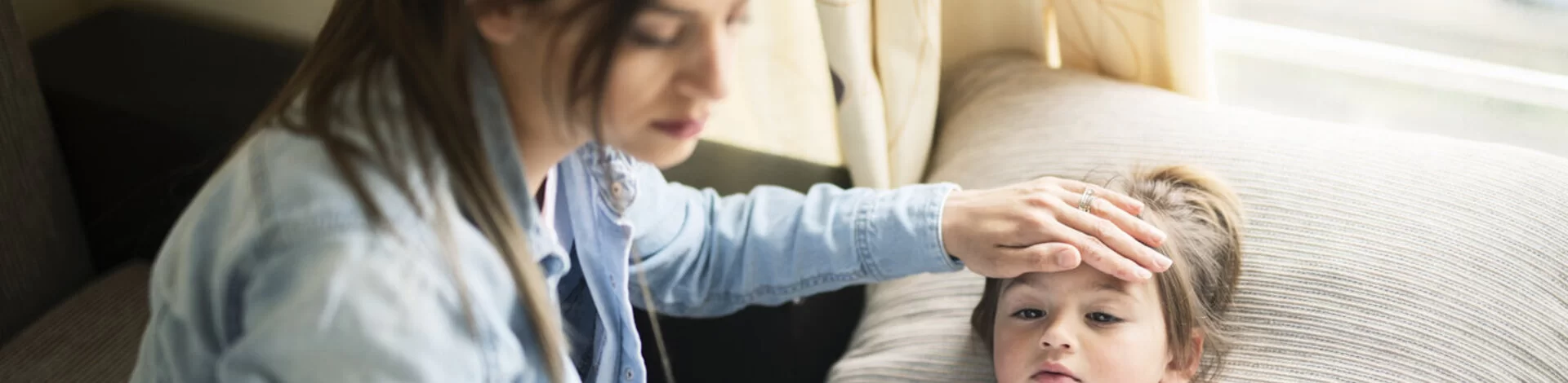Eine Mutter misst Fieber bei ihrer Tochter. Leiden Kinder an einer Mittelohrentzündung, verordnen Ärzte oft Schmerzmittel.