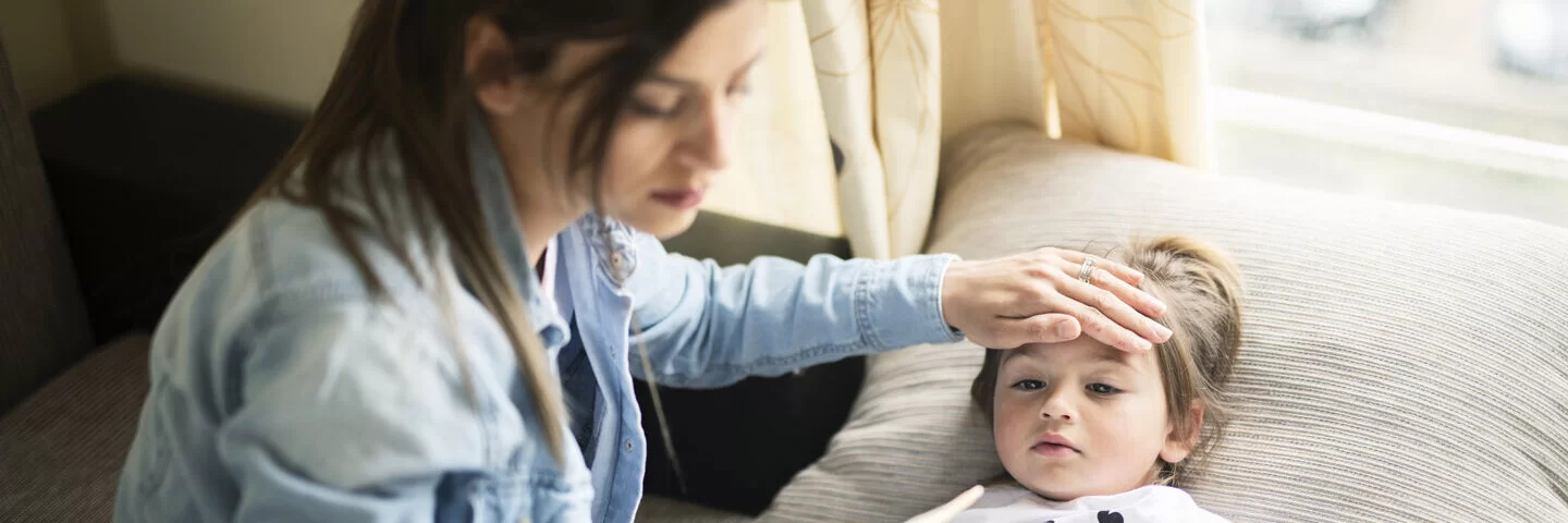 Eine Mutter misst Fieber bei ihrer Tochter. Leiden Kinder an einer Mittelohrentzündung, verordnen Ärzte oft Schmerzmittel.