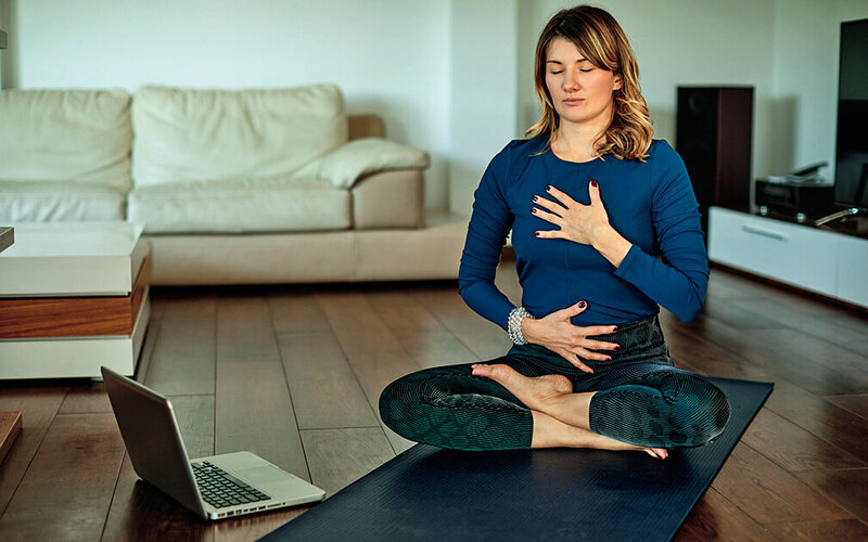 Frau sitzt auf der Yogamatte und trainiert ihre mentale Stärke.