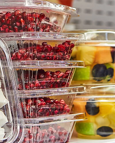 In Plastikbehältern verpacktes Obst, Granatapfelkerne und Kokosnussstücke.