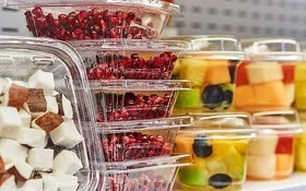 In Plastikbehältern verpacktes Obst, Granatapfelkerne und Kokosnussstücke.