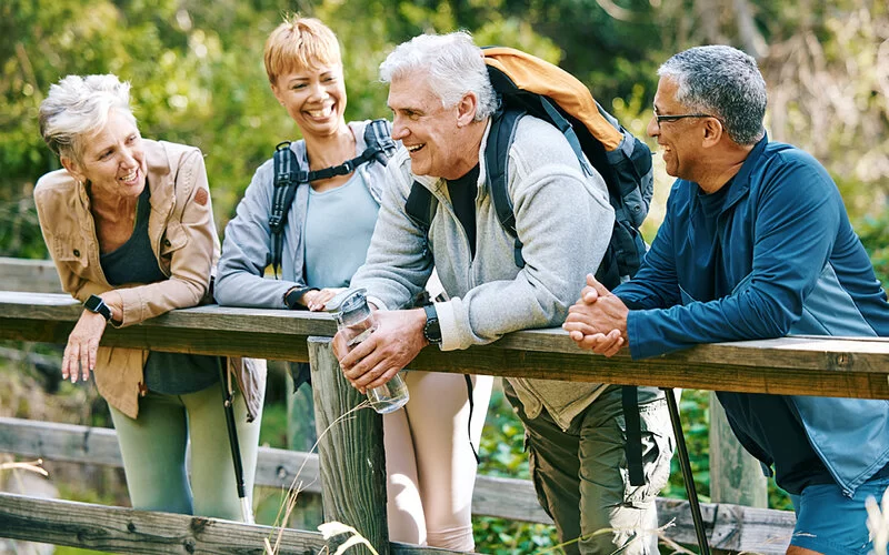 Vier ältere Menschen sind aktiv in der Natur unterwegs.