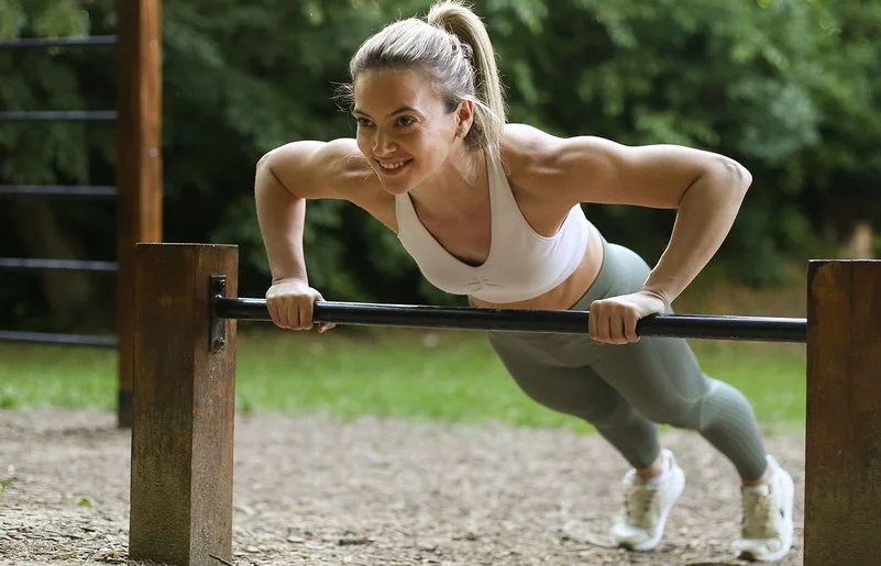 Eine Frau in Sportkleidung macht Liegestütze auf dem Trimm-dich-Pfad.
