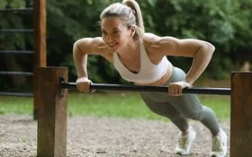 Eine Frau in Sportkleidung macht Liegestütze auf dem Trimm-dich-Pfad.