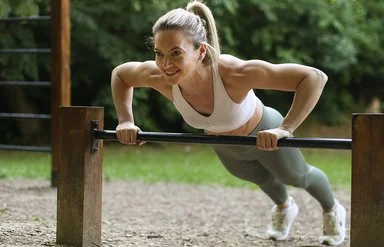 Eine Frau in Sportkleidung macht Liegestütze auf dem Trimm-dich-Pfad.