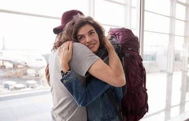 Eine Frau und ein Mann umarmen sich am Flughafen. Auch auf Reisen haben Versicherte der AOK mit der elektronischen Gesundheitskarte automatisch ihren Versicherungsschutz dabei.