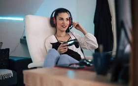 Frau sitzt mit Headset auf einem Sessel und spielt ein Videospiel.