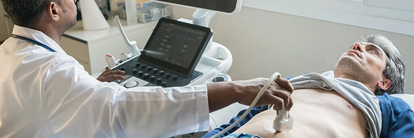 Ein Gastroenterologe untersucht den Bauchraum eines Mannes mit einem Ultraschallgerät.