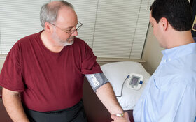 Ein Arzt misst den Blutdruck bei einem älteren Mann mit Übergewicht.