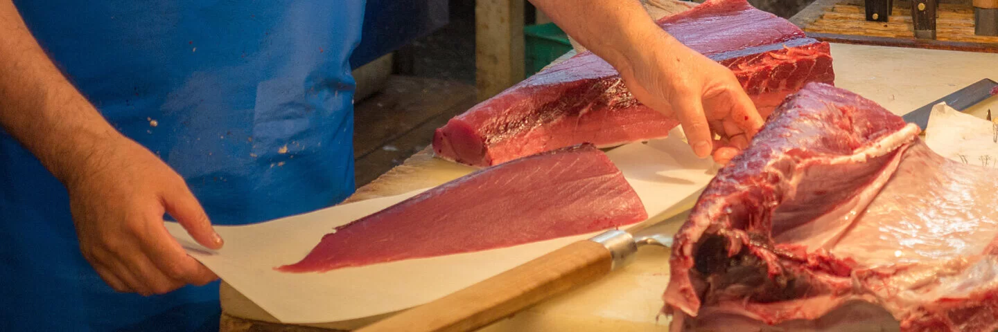 Mann schneidet Thunfisch auf Fischmarkt.
