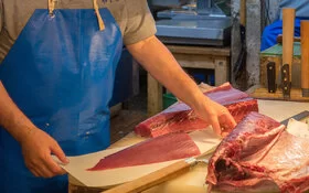 Mann schneidet Thunfisch auf Fischmarkt.