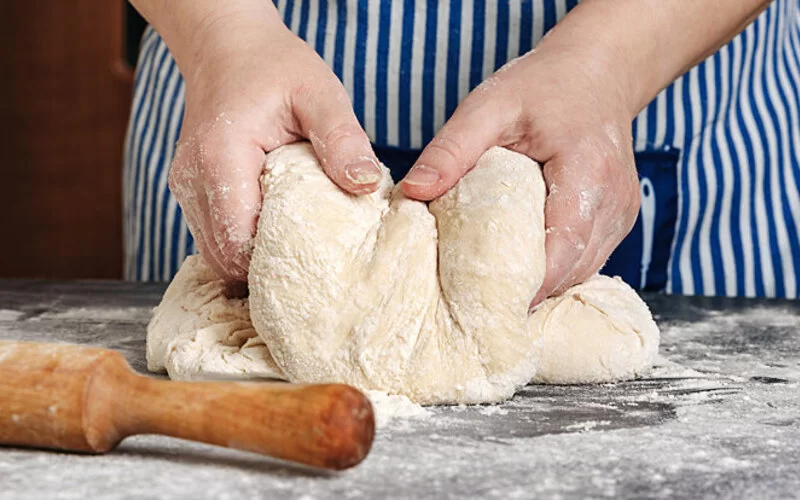 Mann knetet Teig für ein selbstgebackenes Vollkornbrot.