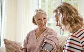 Frau misst den Blutdruck einer älteren Frau mit COPD.
