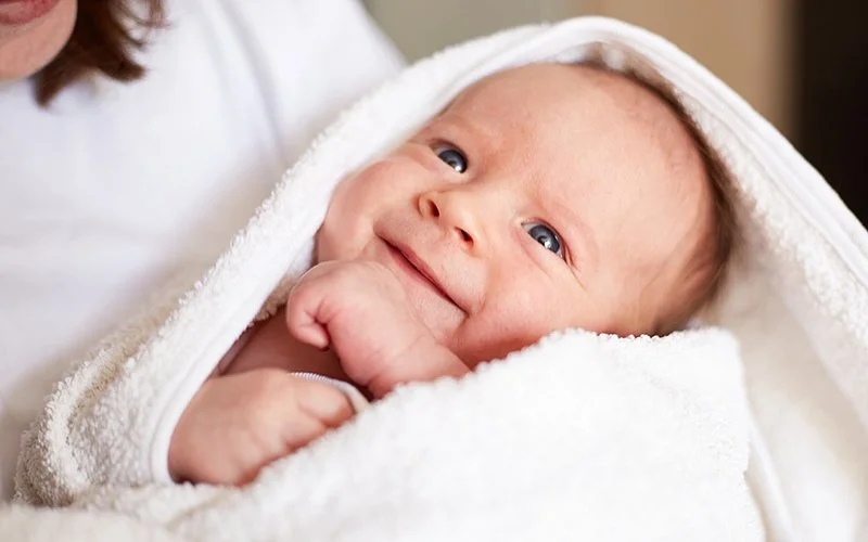 Ein Baby ist in ein weißes Handtuch eingehüllt.