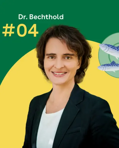Dr. Angela Bechthold steht vor einem grünen Hintergrund. Rechts daneben ist ein blaugrüner Servierteller mit zwei Fischen zu sehen.