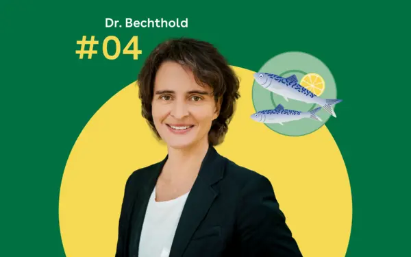 Dr. Angela Bechthold steht vor einem grünen Hintergrund. Rechts daneben ist ein blaugrüner Servierteller mit zwei Fischen zu sehen.