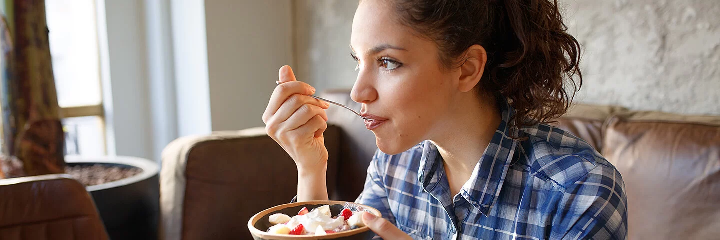 Junge Frau isst Obstsalat und damit garantiert glutenfrei.