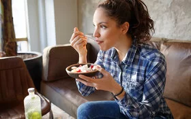 Junge Frau isst Obstsalat und damit garantiert glutenfrei.