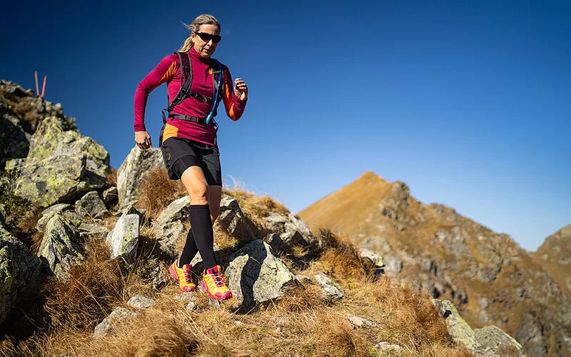 Sportliche Frau beim Joggen in alpiner Landschaft.