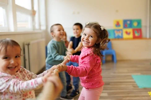 Vier Kinder ziehen im Kindergarten an einem Tau. Im Vordergrund sind zwei Mädchen zu sehen, im Hintergrund zwei Jungen.